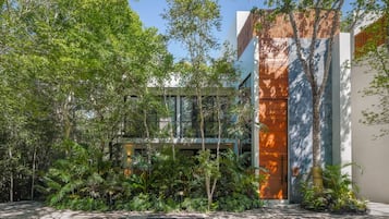Un edificio moderno con fachada de vidrio, rodeado de exuberante follaje y árboles.