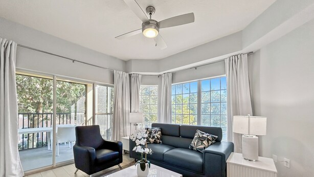 Una sala de estar moderna con sofá, sillón, mesa de centro y ventilador de techo.