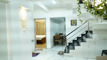 A modern interior with a staircase, a dining area, and a check-in/check-out sign.