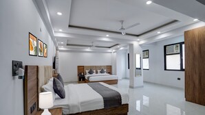 Una habitación de hotel moderna con una cama grande, mesitas de noche, ventilador de techo y obras de arte en las paredes.