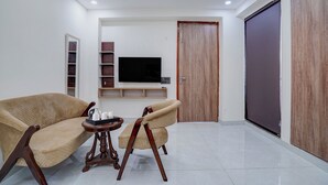 Una sala moderna con un sofá, dos sillones, una mesita de centro y un televisor de pantalla plana montado en la pared.