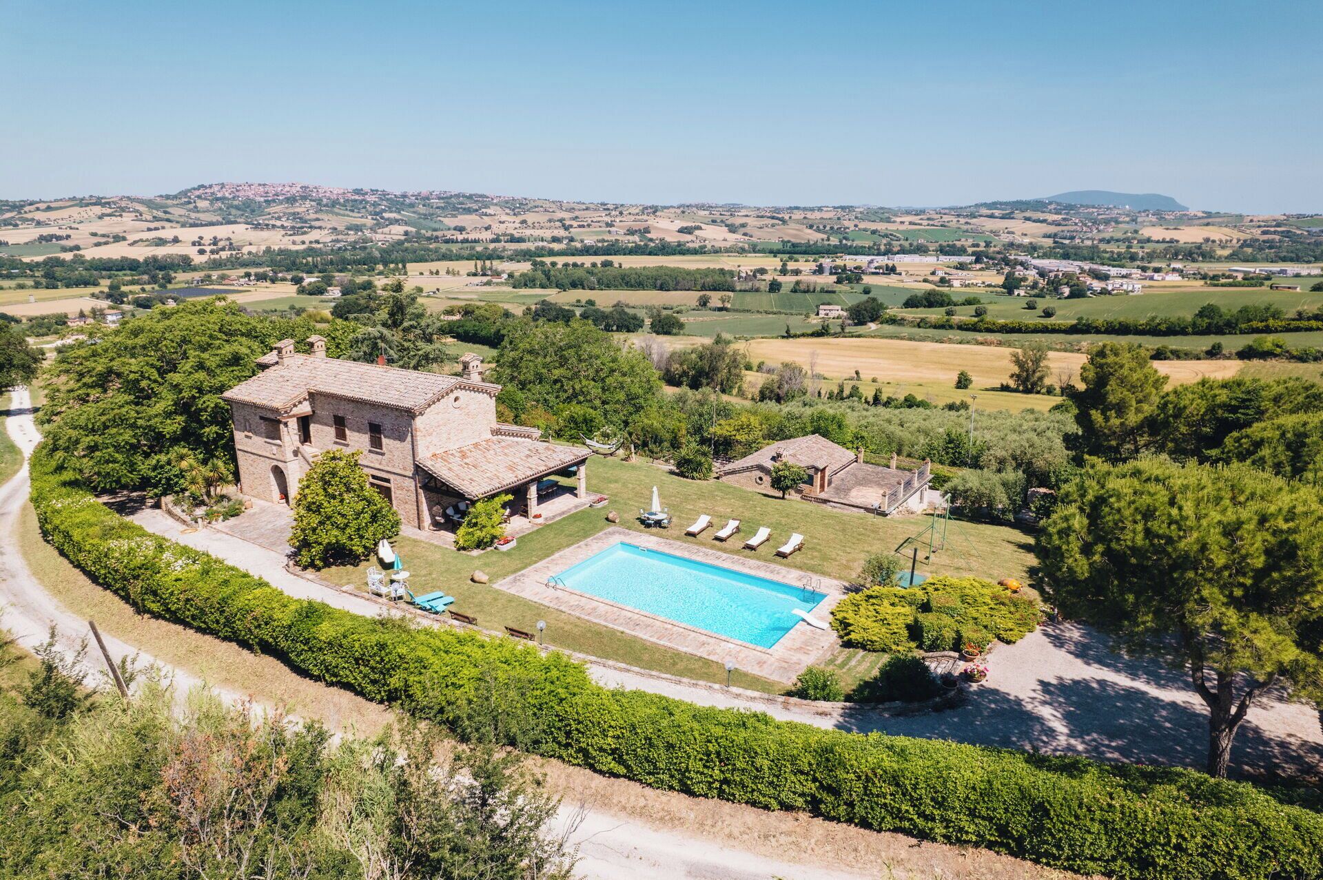 Une villa avec piscine, entourée d’une végétation luxuriante et offrant une vue pittoresque sur la campagne environnante.