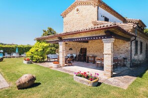A brick building with a covered patio, outdoor seating, and a stone barrel. - Private Villa with private pool, WIFI, A/C, TV, terrace, panoramic view, close to Porto Recanati (Potenza Picena)