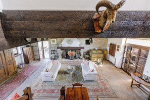 A rustic living room with a fireplace, white sofas, and a wooden table.