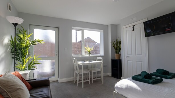 A modern bedroom with a bed, a desk, and a sofa. - Donnington Apartments - Studio 5 (Telford and Wrekin)