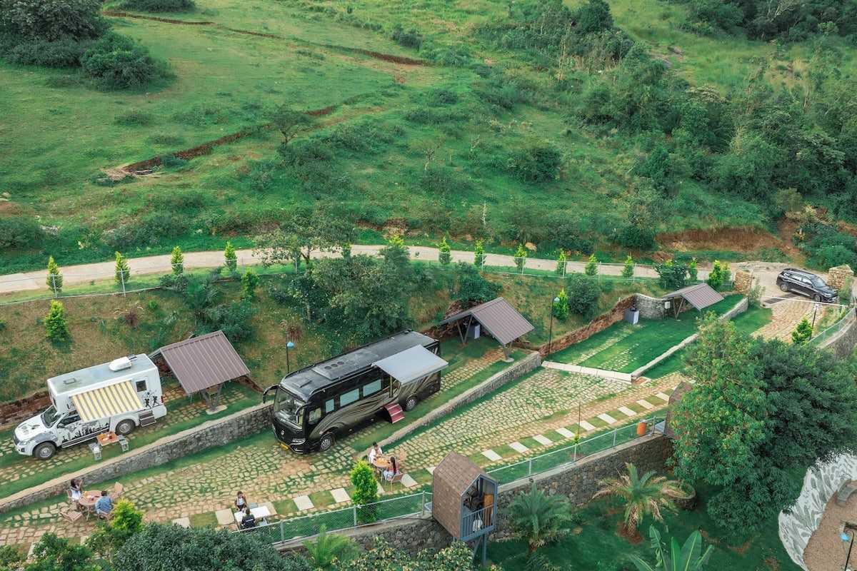 An RV park with a paved patio area, a covered picnic table, and a stone wall.
