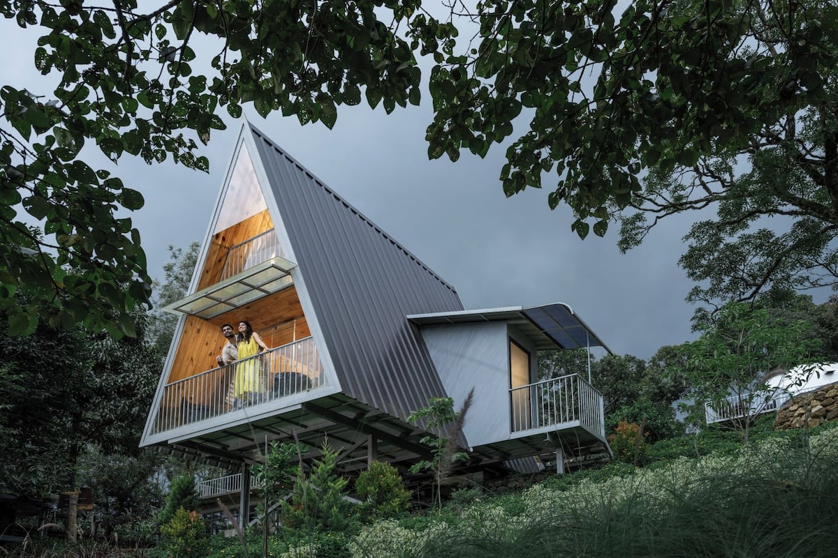 A modern, triangular house with a balcony and a small attached structure.