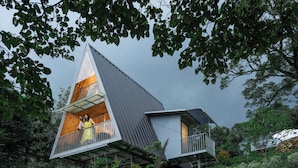 A modern, triangular-shaped house with a balcony, surrounded by lush greenery. - Vanani Resort and Caravan Park Munnar (Udumbanchola)