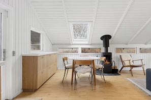 Moderni keittiö, jossa on puiset kaapit, pyöreä ruokapöytä ja sisäänrakennettu puuliesi.