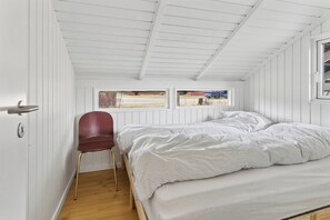 Een slaapkamer met een bed, een stoel, een raam en een radiator.