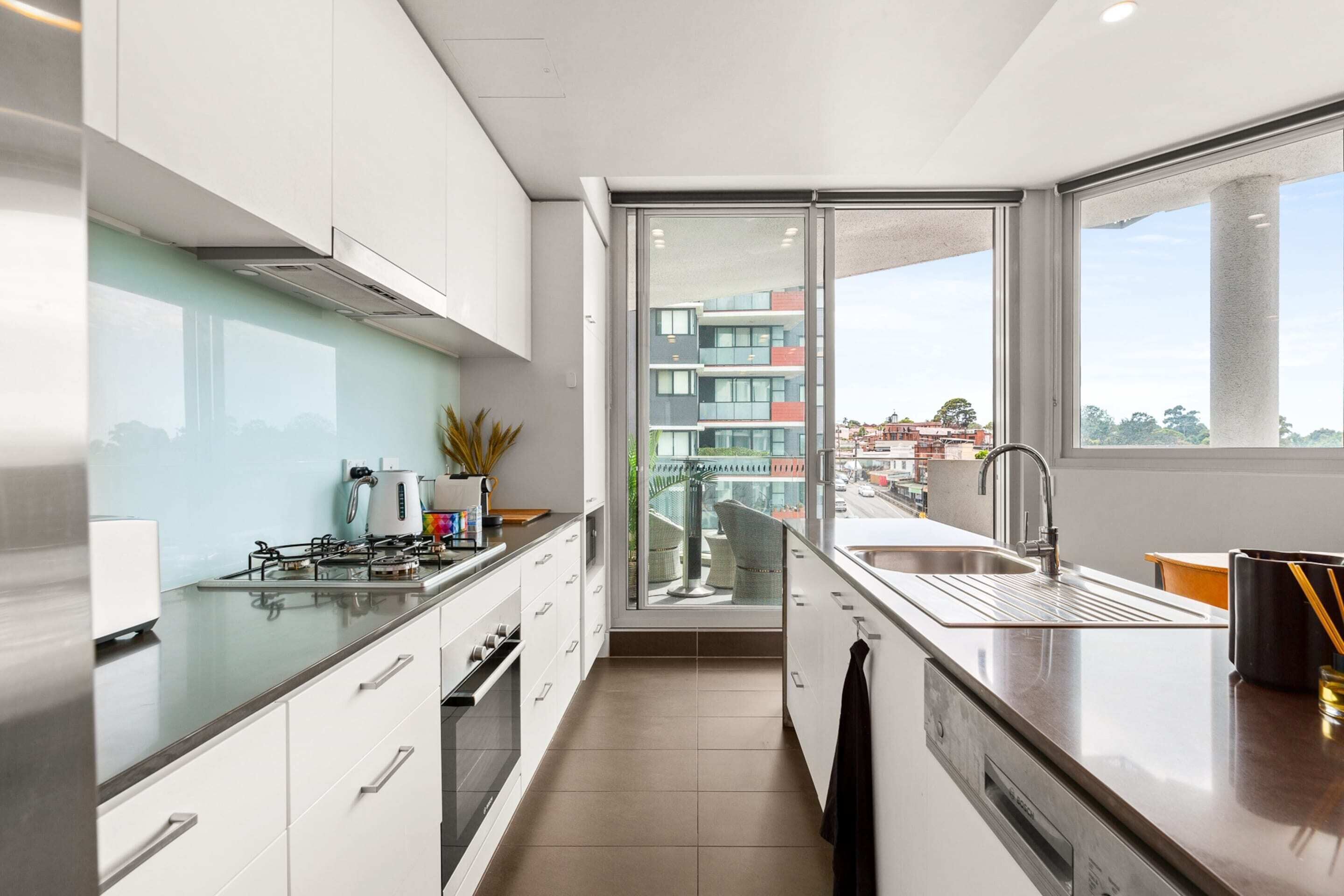A modern kitchen with a large window, a gas stove, and a sink.
