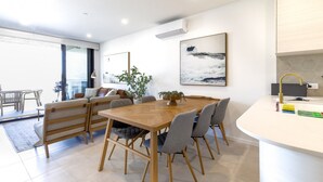 Un espace repas moderne avec une table et des chaises en bois, une plante en pot et un tableau au mur.
