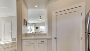 Una cucina moderna con mobili bianchi, un frigorifero in acciaio inox e una ventola a soffitto.