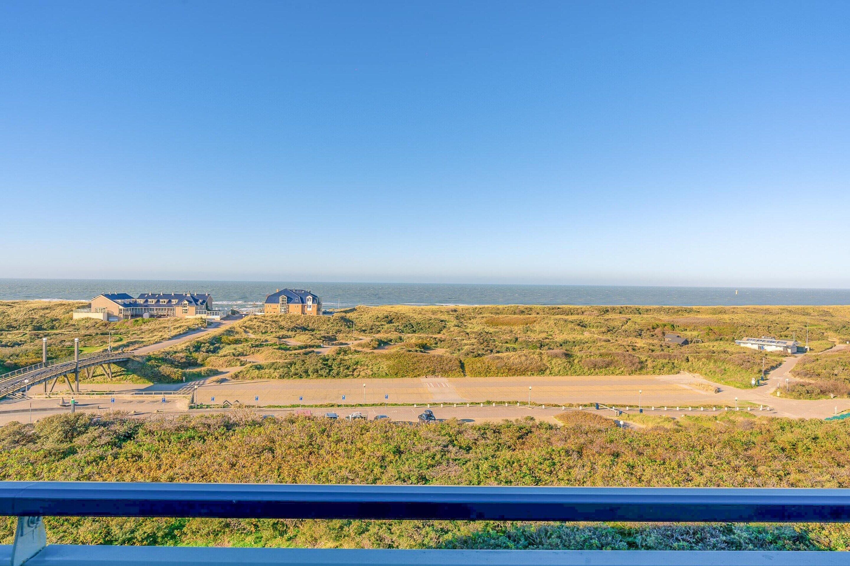 Une vue côtière avec des bâtiments, un pont et une route menant à la mer.