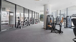 A modern gym with various exercise machines, large windows, and a clean, spacious layout. - 2-bed, 500m From The Beach With Pool, Gym & Sauna (Melbourne)