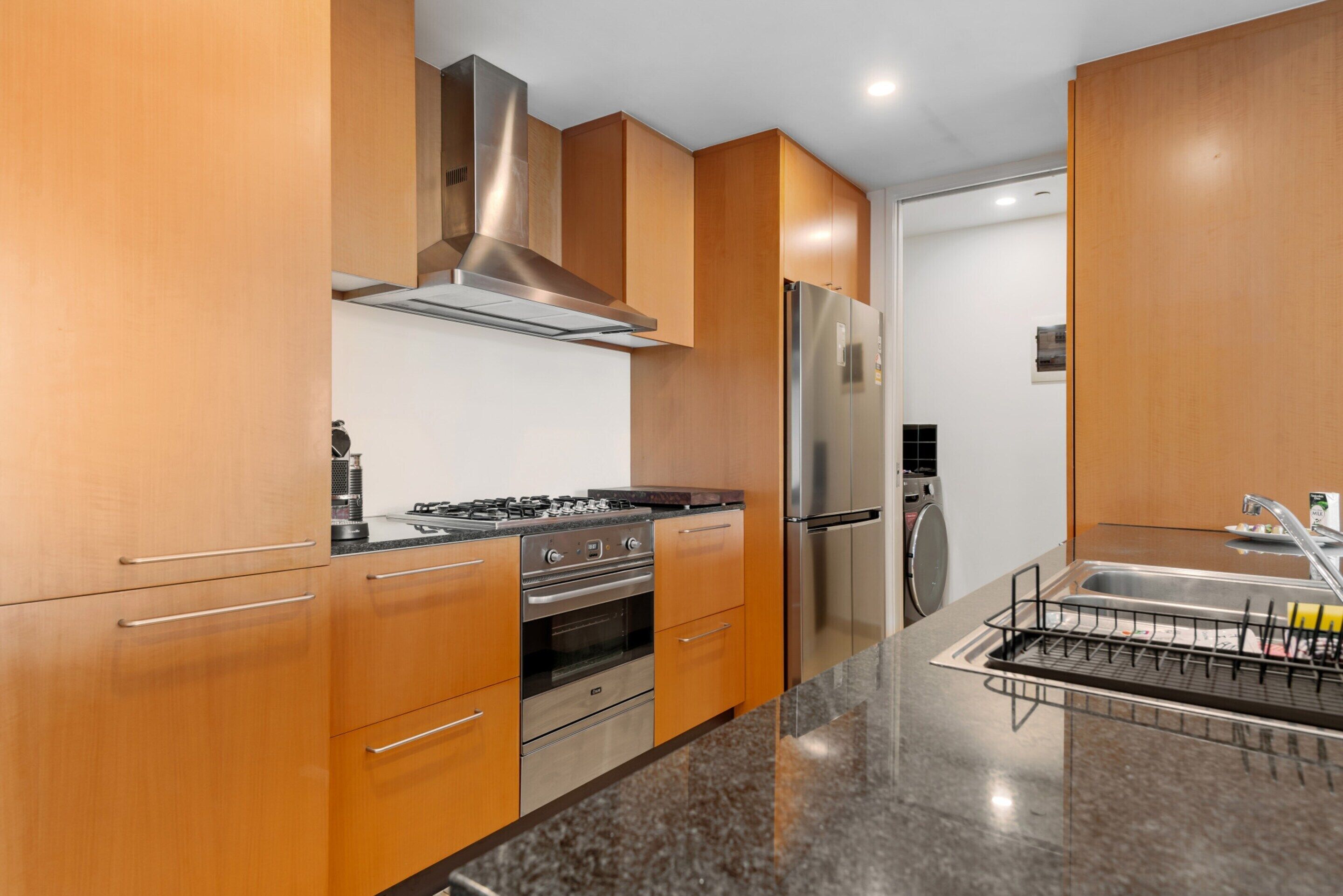 Una cocina moderna con armarios de madera, electrodomésticos de acero inoxidable y encimera de granito.