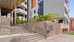 A modern building with a staircase leading to an entrance, a large number '895' on the wall, and a clear sky. - 2-bed, 500m From The Beach With Pool, Gym & Sauna (Melbourne)