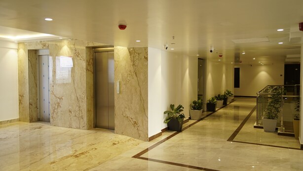 A modern hotel lobby with marble flooring, a glass railing, and potted plants. - A79 by Khotels (Chennai)