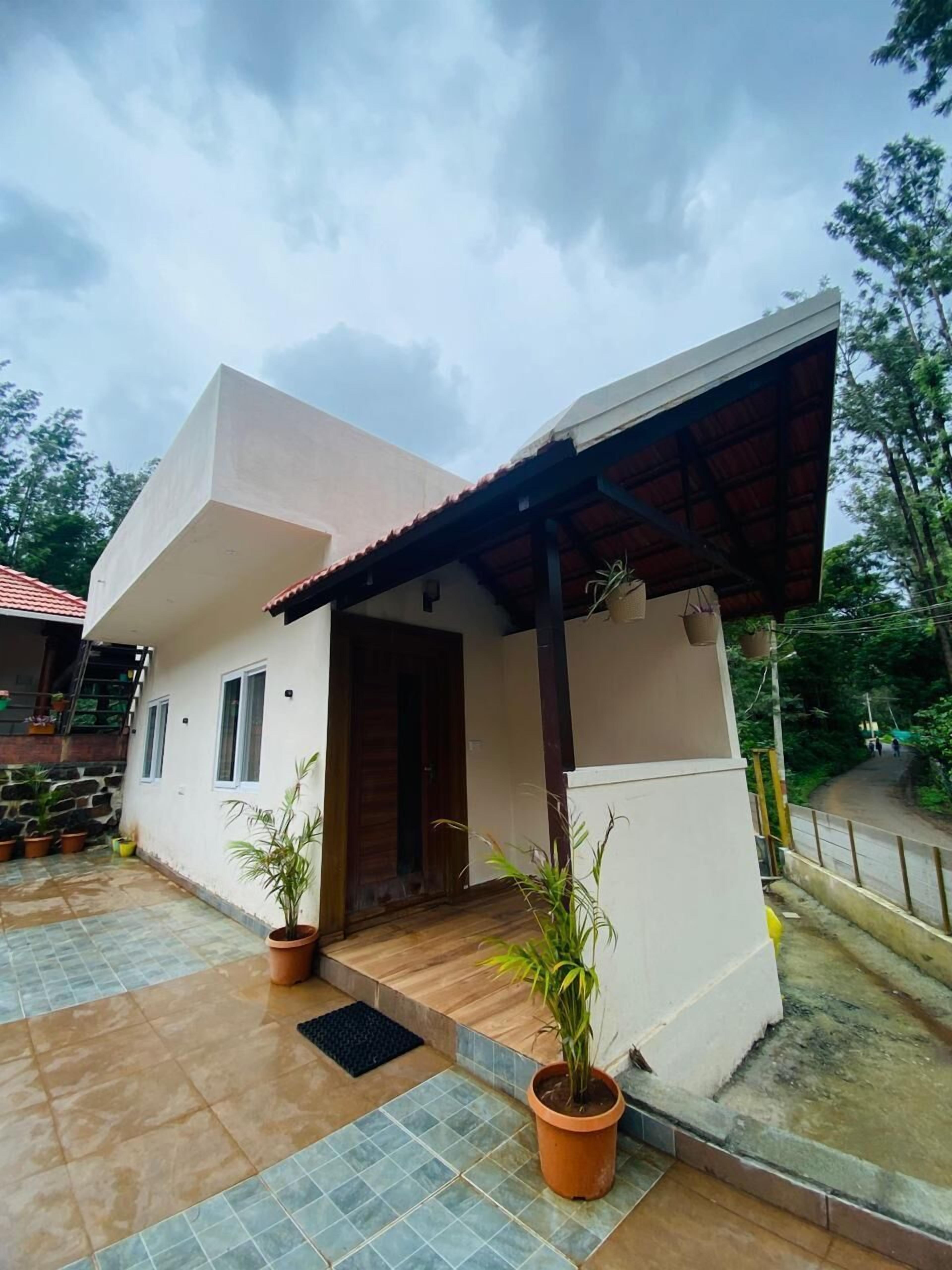 A modern house with a tiled patio, a wooden door, and potted plants.