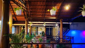 A covered outdoor area with wooden columns, potted plants, and a staircase. - Commune Homes Chikmagalur (Chikkamagaluru)