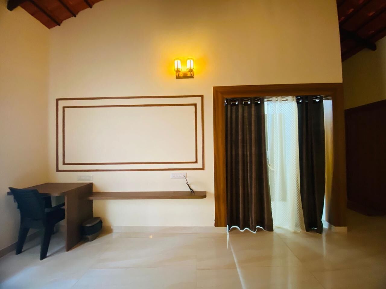 A room with a desk, chair, and a wall-mounted light fixture.