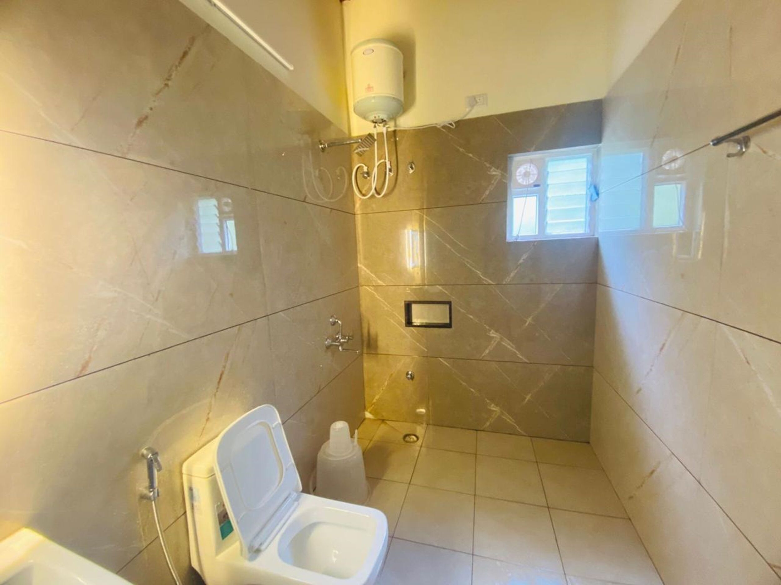 Une salle de bain avec une douche, des toilettes et une petite fenêtre.