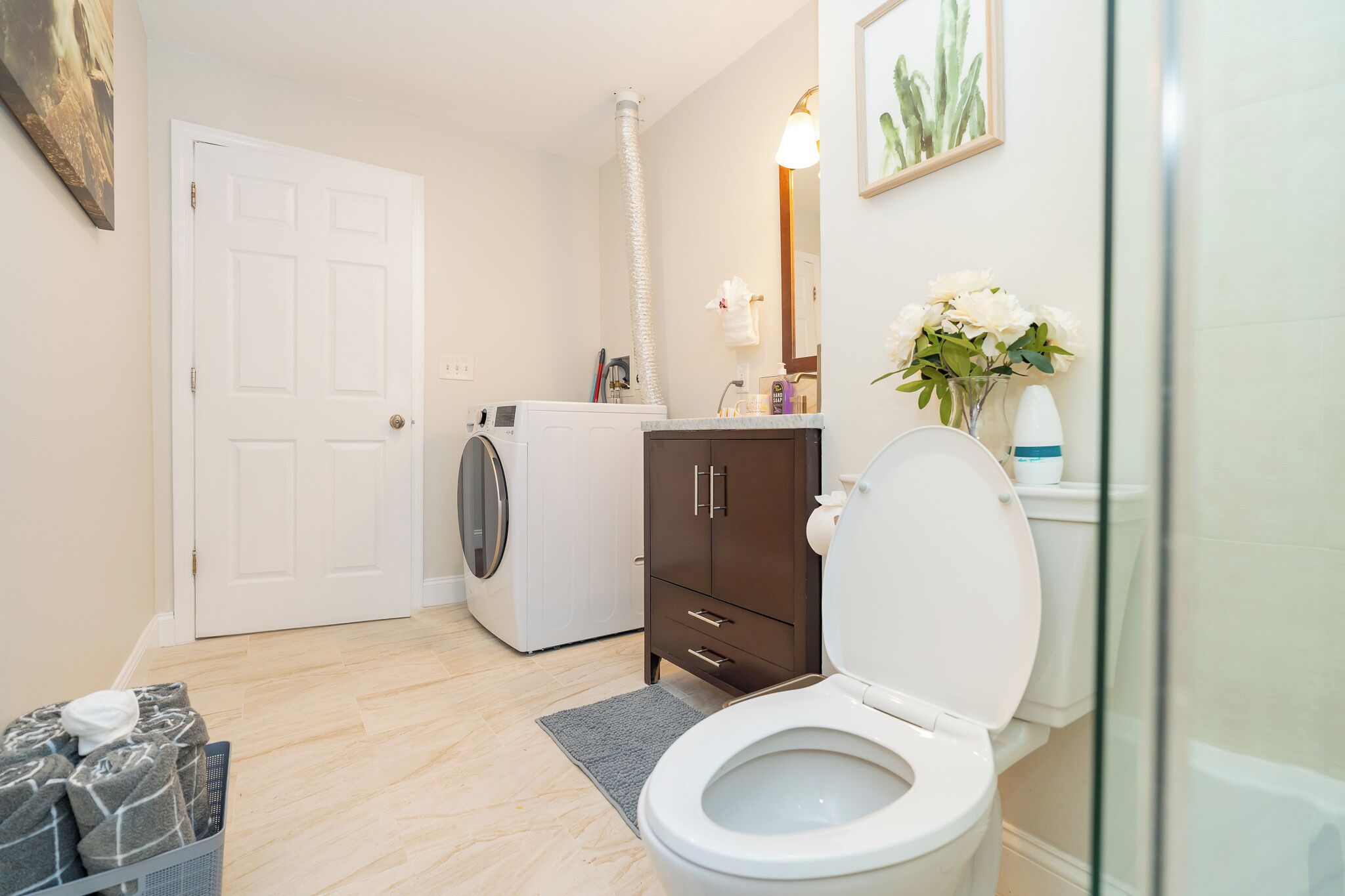 A compact bathroom with a toilet, washing machine, and a cabinet.