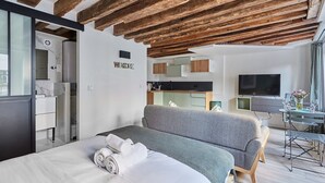 Une chambre d’hôtel moderne équipée d’un lit, d’un canapé, d’une télévision et d’un coin cuisine.