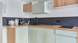 Une cuisine moderne avec un plan de travail en bois, un pare-feu noir et des armoires vert clair.