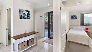 Un dormitorio moderno con cama, mesita de noche, ventana con vistas y baño visible a través de una puerta abierta.