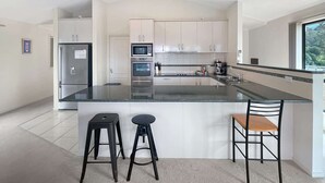 Cocina moderna con una isla central, electrodomésticos de acero inoxidable y vistas a zonas verdes.