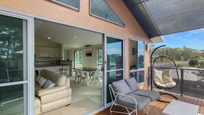Una casa moderna con balcón, comedor y sala de estar con sofá y sillones.