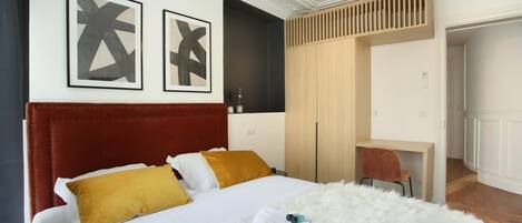 Une chambre d’hôtel avec un grand lit, un bureau et une armoire.