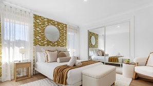 A modern bedroom with a bed, bedside tables, a chair, and a large mirror. - Charming Forrestfield Escape! (Forrestfield)