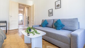 A living room with a grey sofa, two blue cushions, a white coffee table with a plant, and a black chair. - Comfy 2BR Apt Long Stay Matzleinsdorfer (Vienna)