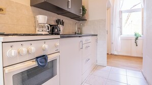 A kitchen with a stove, oven, and coffee maker. There is a window with a view of the outside. - Comfy 2BR Apt Long Stay Matzleinsdorfer (Vienna)