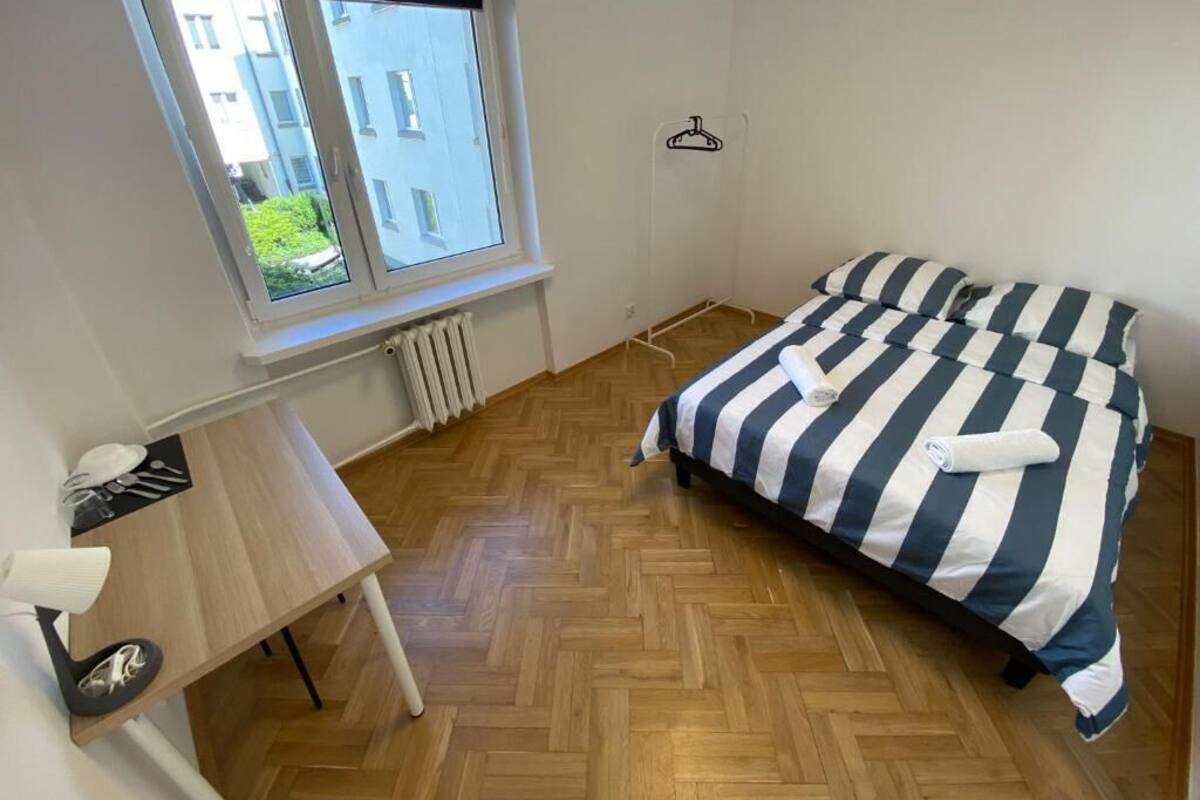 Une petite pièce propre et bien rangée, avec un lit, un bureau et une fenêtre.