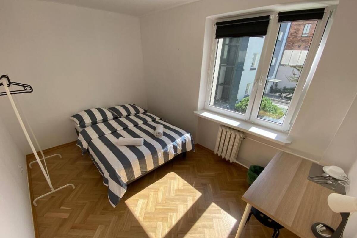 Une petite pièce lumineuse, avec un lit, un bureau et une fenêtre.