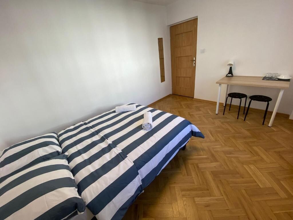 A room with a bed, a desk, two chairs, and a door.