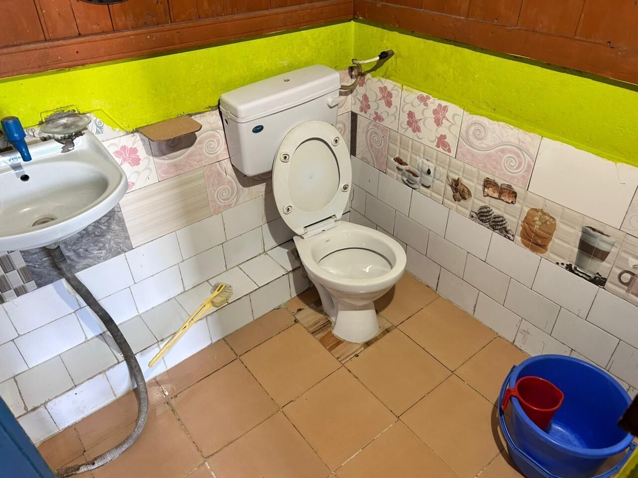 A bathroom with a toilet, sink, and a blue bucket.