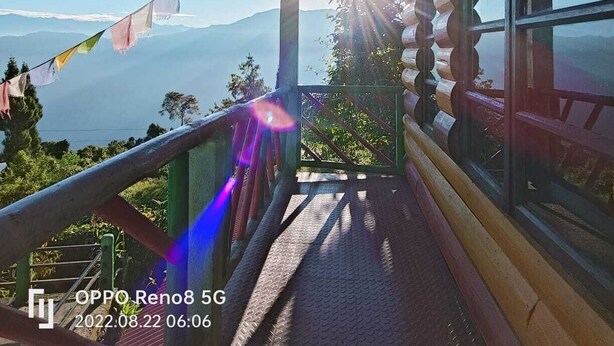 A wooden cabin with a balcony overlooking a mountainous landscape. - Paradise Homestay (Kalimpong)