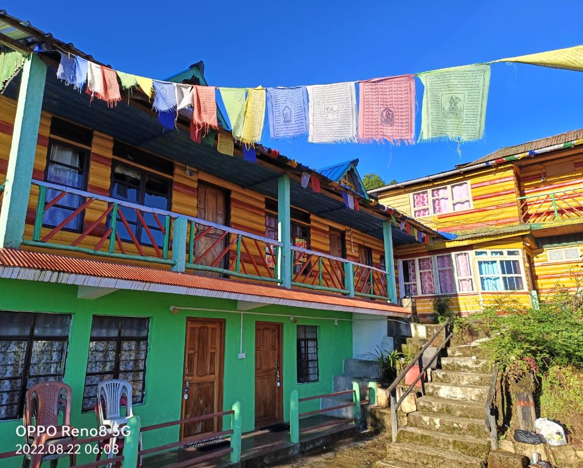 Un edificio colorido de dos pisos con fachada verde, balcones de madera y una escalera que lleva al piso superior.