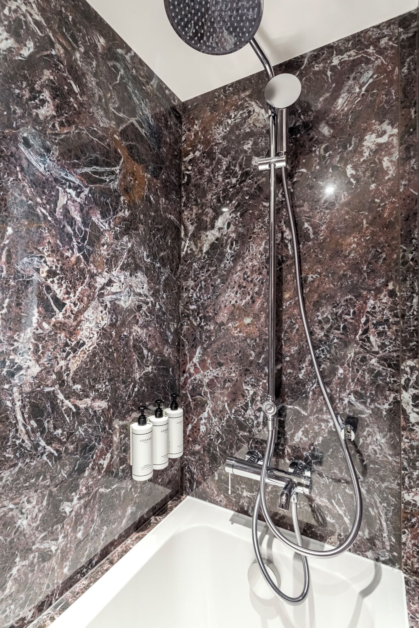 Ein Badezimmer mit Dusche, Badewanne und Marmorwänden.