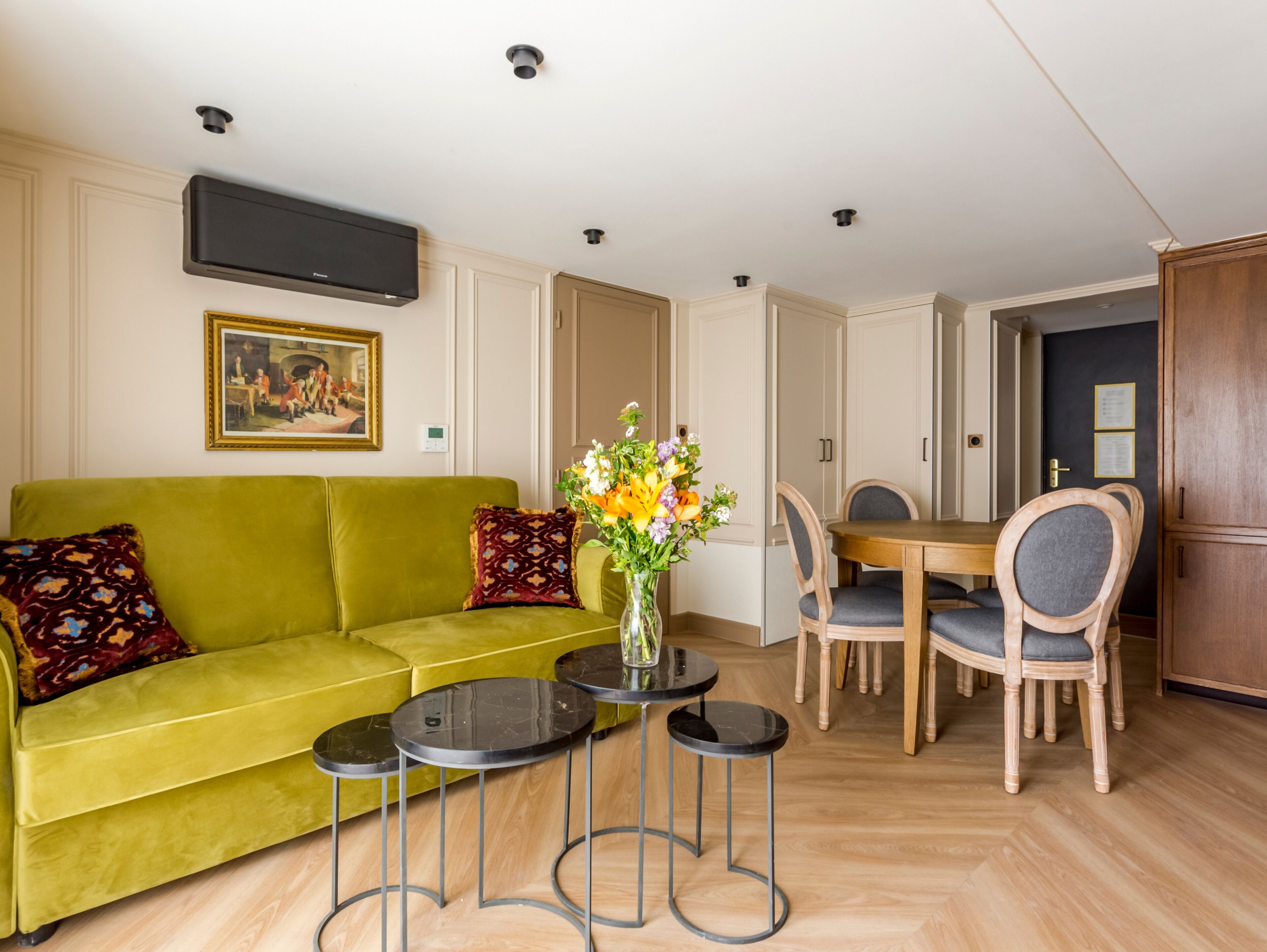 A living room with a green sofa, a coffee table, and a dining table with chairs.