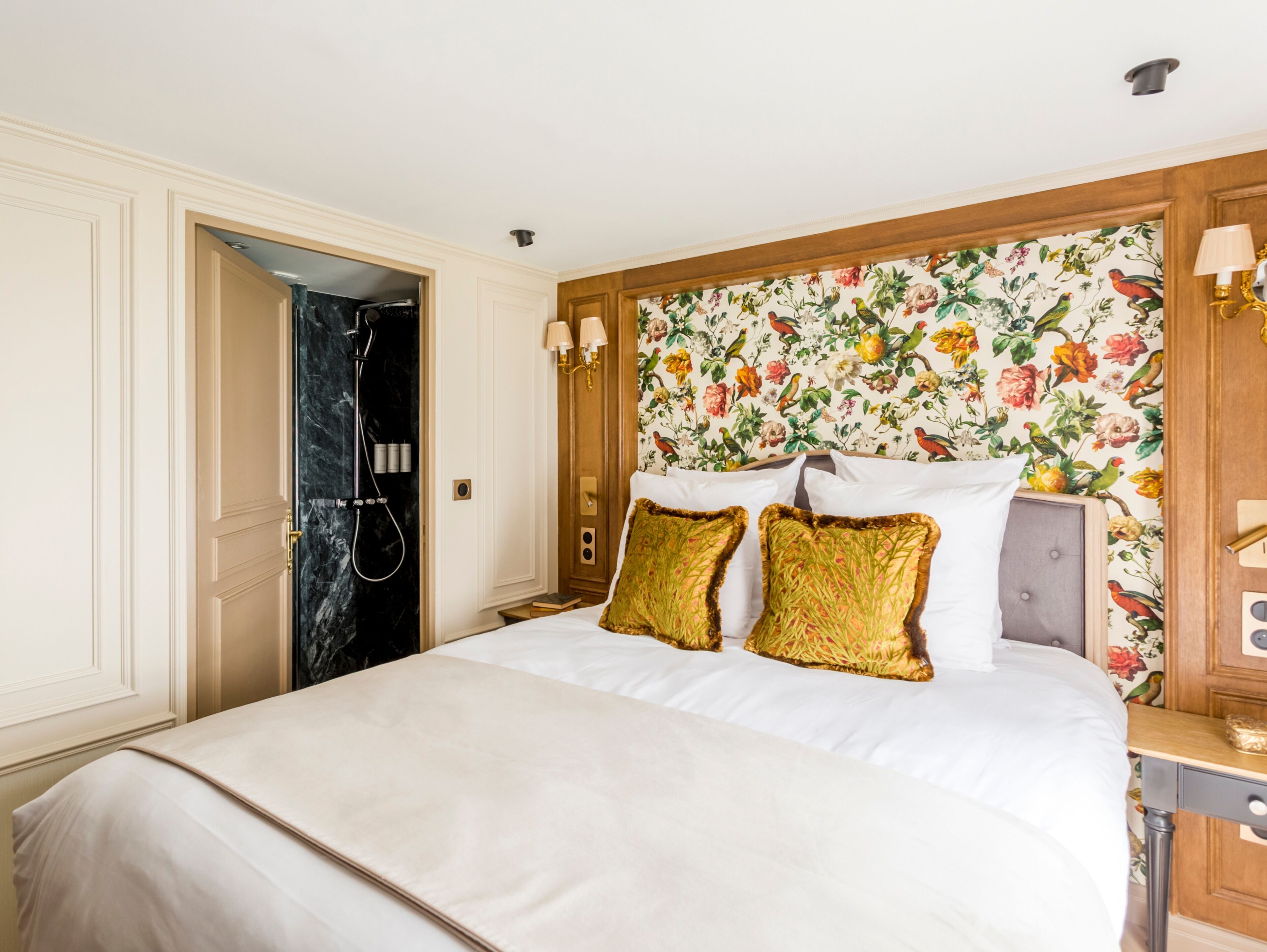 A hotel room with a bed, a shower, and a floral wallpaper.