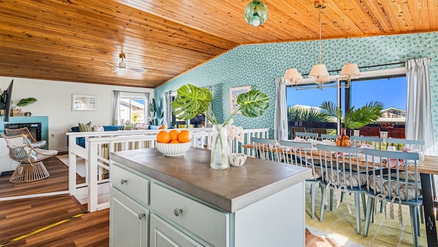 A modern kitchen with a wooden ceiling, a dining area with a table and chairs, and a large window with curtains. - Ocean Views • Private Pool • Walk to Beach (St. Augustine)