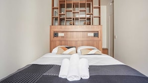 A hotel room with a large bed, wooden headboard, and built-in shelving above the bed. - New Apartment Center of Paris Le Marais (Paris)