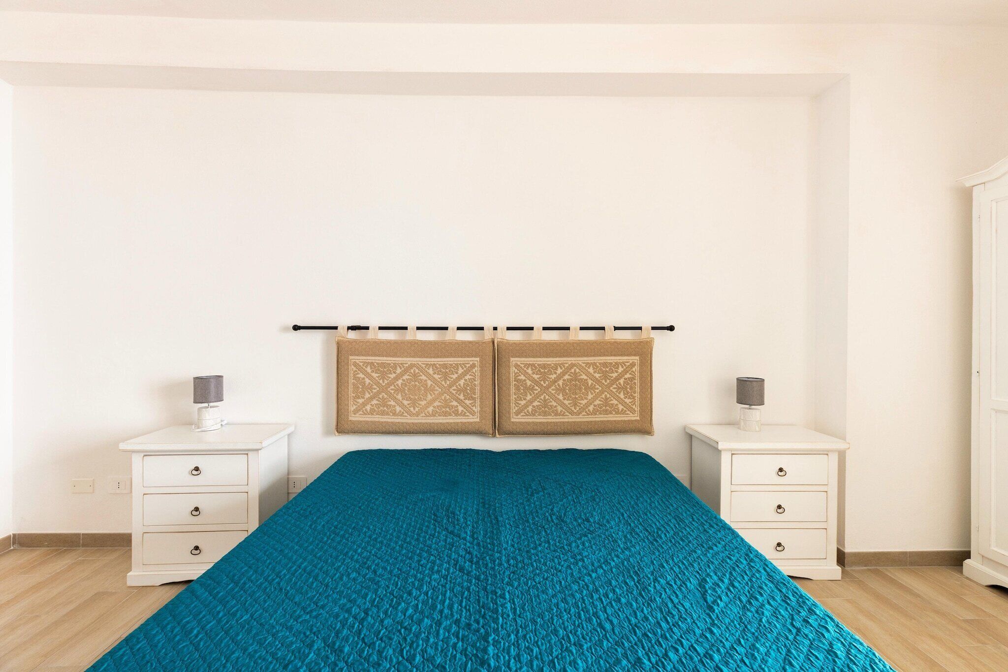 Un dormitorio con una cama, dos mesitas de noche y un armario.