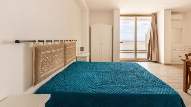 Une chambre avec un grand lit, une armoire et une vue sur l’extérieur.