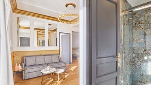 Ein modernes Hotelzimmer mit einer grauen Couch, einem kleinen runden Tisch und einem großen Spiegel.